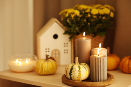 Burning candles, pumpkins and autumn decor on white tableの写真素材