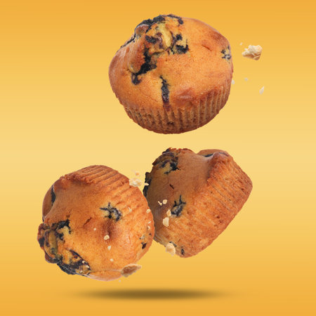 Delicious blueberry muffins falling on golden backgroundの写真素材