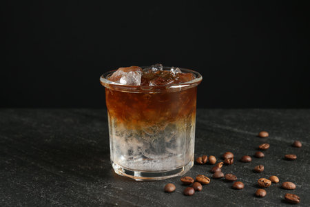 Refreshing espresso tonic drink and coffee beans on dark table