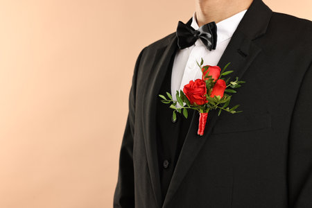 Groom in suit with stylish boutonniere on beige background, closeup. Space for textの写真素材