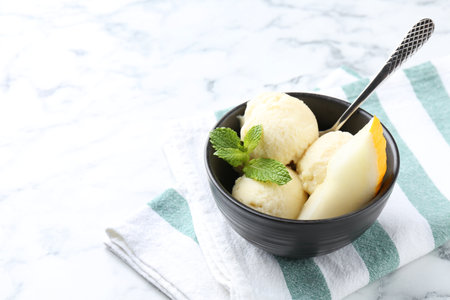Scoops of tasty melon sorbet with mint and spoon in on white marble table, space for textの写真素材