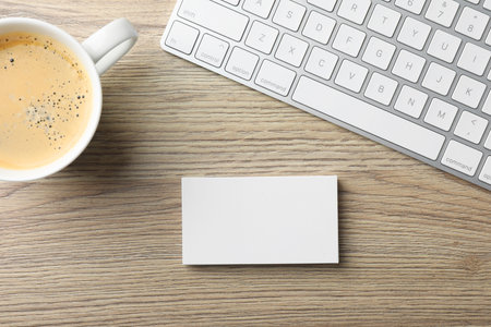 Blank business cards, coffee and keyboard on wooden table, flat lay. Mockup for designの写真素材