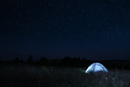 Modern camping tent in wilderness at nightの写真素材