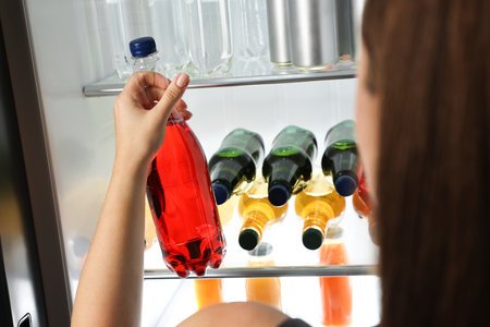Woman taking bottle with drink from refrigerator, closeupの写真素材