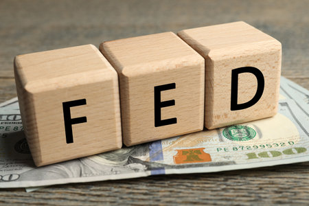 Wooden cubes with letters Fed (Federal Reserve System) and dollar banknotes on table, closeup