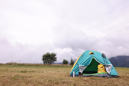 Camping tent and tourist stuff on grass in mountains, space for textの写真素材