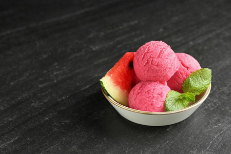 Scoops of tasty watermelon sorbet with mint and fresh fruit in bowl on gray textured table, space for textの写真素材