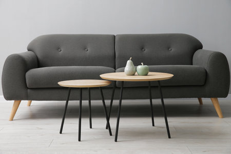 Comfortable sofa and tables near gray wall in room