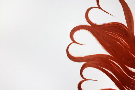 Red hair strands in shape of hearts on white background, top view. Space for textの写真素材