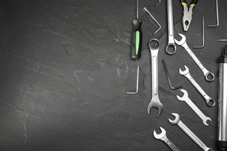 Parts of bicycles and tools on black table, flat lay. Space for text