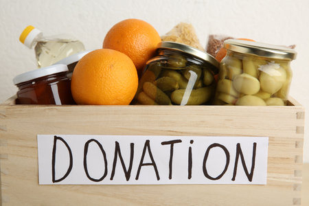 Donation food products in wooden crate on light background, closeupの写真素材