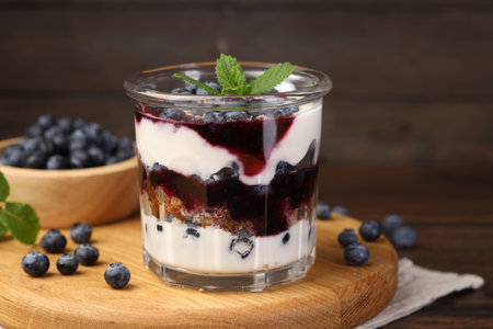 Tasty trifle dessert. Blueberries, sponge cake and whipped cream in glass on wooden tableの写真素材
