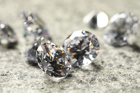 Many beautiful shiny diamonds on gray table, closeup