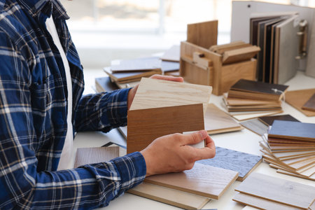 Man choosing wooden flooring among different samples at table, closeupの写真素材