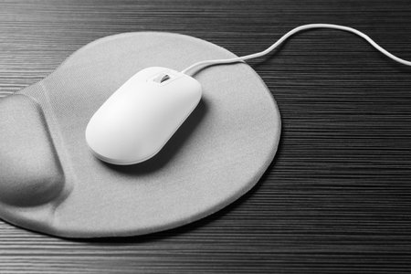 Computer mouse and mousepad with armrest on black wooden table