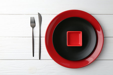Stylish plates, cutlery and sauce bowl on white wooden table, top viewの写真素材