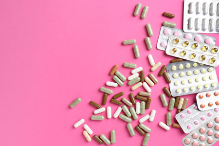 Pharmacist concept. Flat lay composition with many different pills on pink background, space for textの写真素材