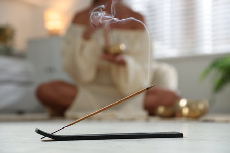 Incense stick smoldering in holder on floor indoors, selective focusの写真素材