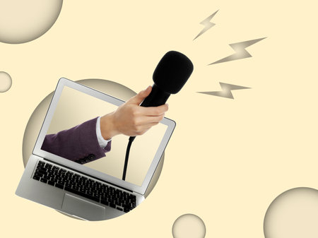 Journalist's hand with microphone sticking out of laptop on color background. creative collageの写真素材