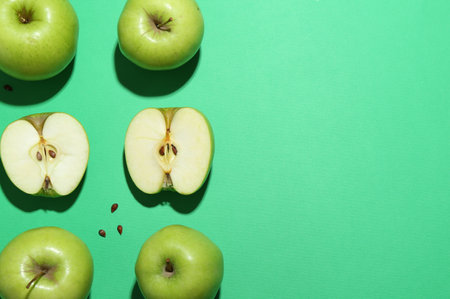 Flat lay composition with whole, cut apples and seeds on green background. Space for textの写真素材