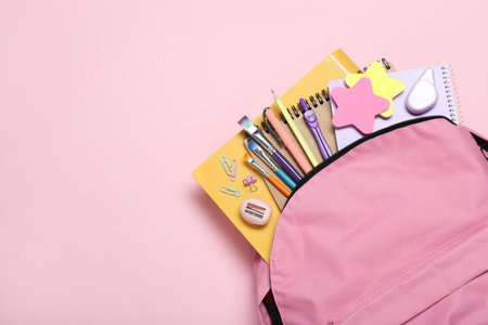 Backpack and different school stationery on pink background, top view. Space for text