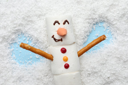 Marshmallow snowman making angel on artificial snow, top viewの写真素材