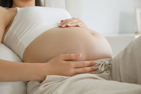 Young pregnant woman lying on bed at home, closeupの写真素材