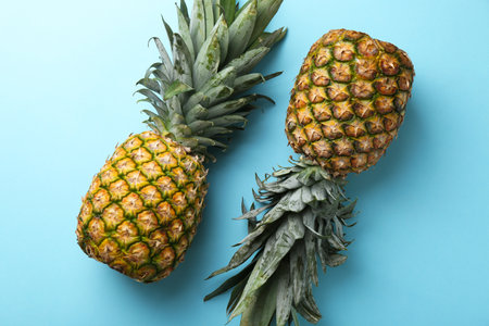 Fresh ripe pineapples on light blue background, top view