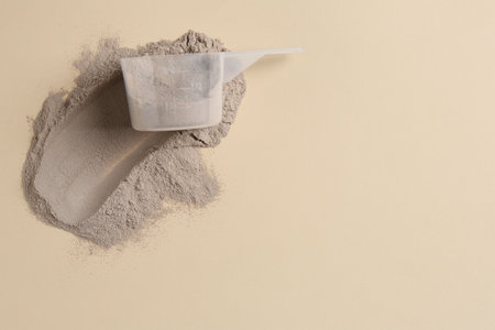 Protein powder and scoop on beige background, top view. Space for textの写真素材