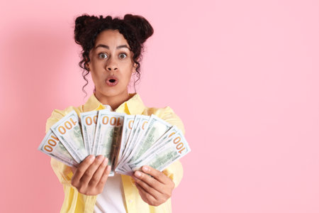 Shocked woman with dollar banknotes on pink background, space for textの写真素材