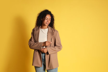 Beautiful woman in stylish jacket on yellow background. Space for textの写真素材