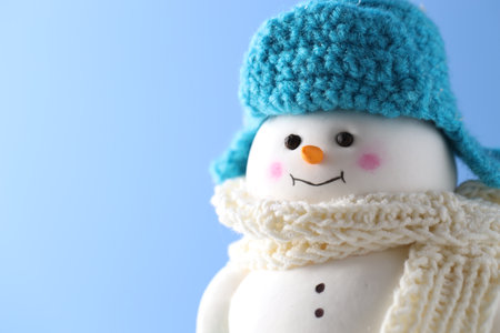 Cute decorative snowman against light blue background, closeup. Space for textの写真素材