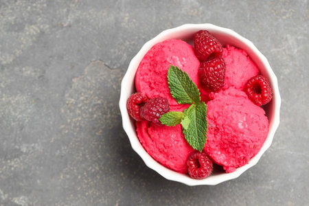 Delicious raspberry sorbet, fresh berries and mint in bowl on gray textured table, top view. Space for textの写真素材