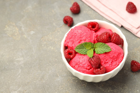 Delicious raspberry sorbet, fresh berries and mint in bowl on gray textured table, space for textの写真素材