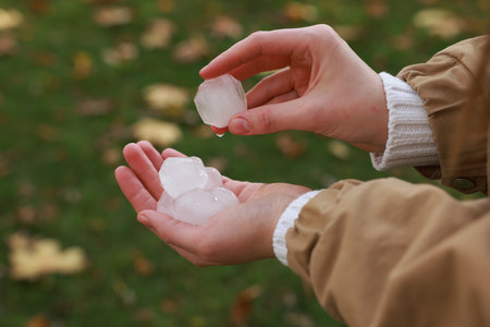 Woman holding hail grains after thunderstorm outdoors, closeup
