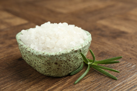 Sea salt and rosemary in bowl on wooden table, closeupの写真素材