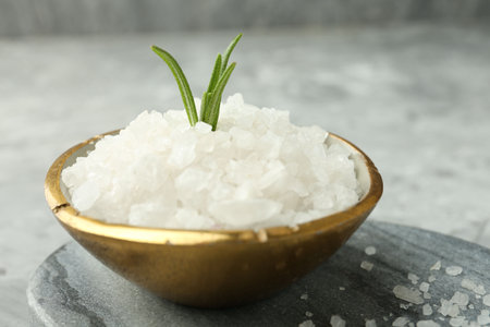 Sea salt and rosemary in bowl on gray table, closeupの写真素材