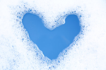 Heart shape made of detergent foam in water, top view. Hand washing laundryの写真素材