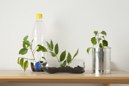 Recycling concept. Metal can and plastic bottles with plants on wooden tableの写真素材