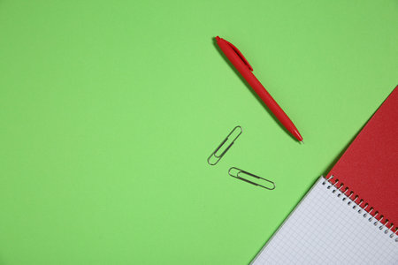 Notebook, paper clips and pen on light green background, top view. Space for textの写真素材