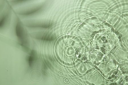 Rippled surface of clear water on light green background, top viewの写真素材