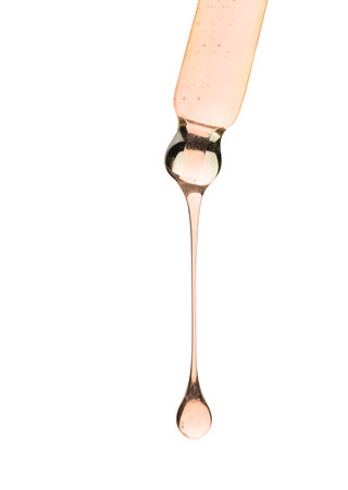 Cosmetic oil dripping from pipette on white background, closeupの写真素材