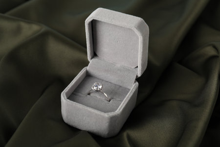 Beautiful ring with gemstone in box on dark fabric, closeup