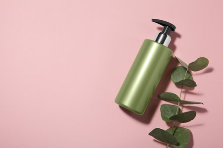 Bottle of shampoo and eucalyptus branch on pink background, flat lay. Space for textの写真素材