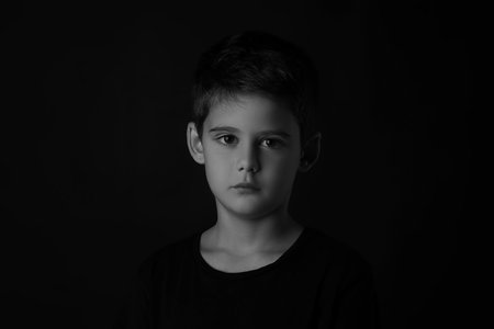 Portrait of sad little boy on dark background. Black and white effectの写真素材