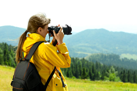 Photographer with backpack and camera taking picture of beautiful mountains. Space for text