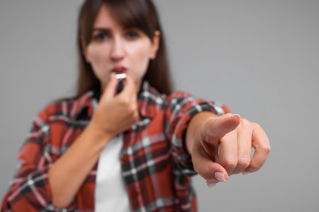 Woman blowing whistle on gray background, selective focusの写真素材