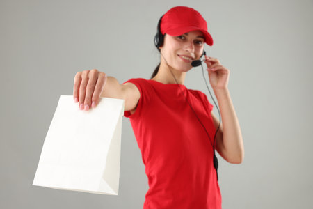 Food service worker with paper bag on gray background, selective focusの写真素材
