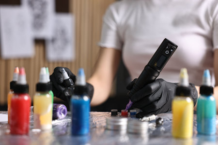 Professional artist working with tattoo machine and inks at sterile table in salon, closeupの写真素材