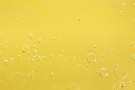 Essential oil bubbles on yellow background, macro view. Cosmetic productの写真素材